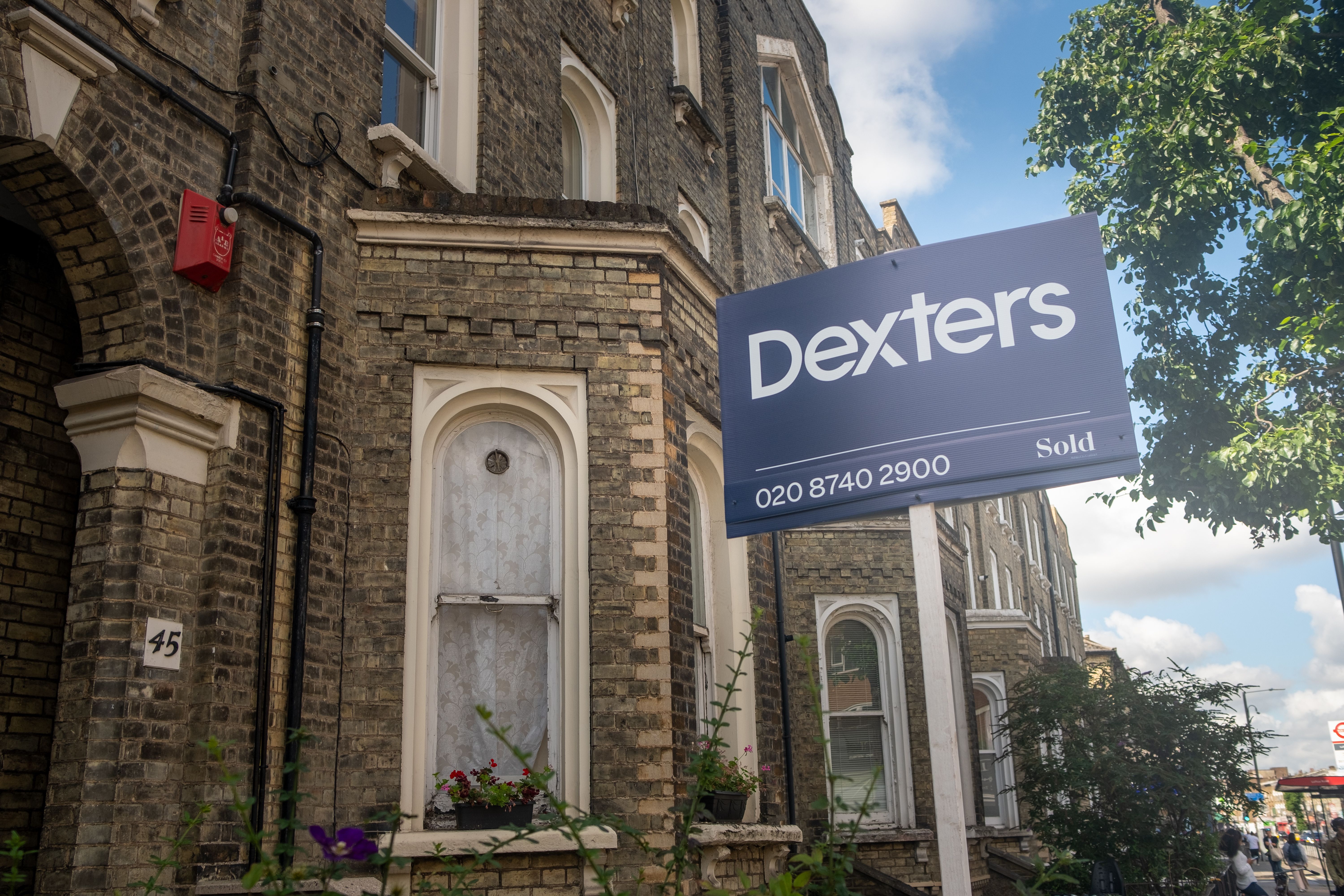 A clean, modern navy blue estate agent sign with a minimal design, placed outside a set of properties to attract attention and promote the listing.