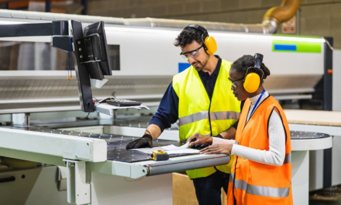 Two print professionals operating an aluminium board printing machine during the production process.