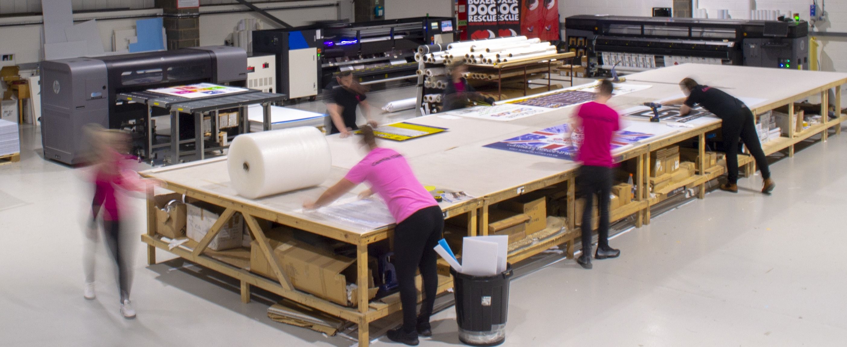 Carrick Signs graphic asking 'Which Material Is The Best for Outdoor Banners?' with examples of pink geometric banner materials and company contact details.