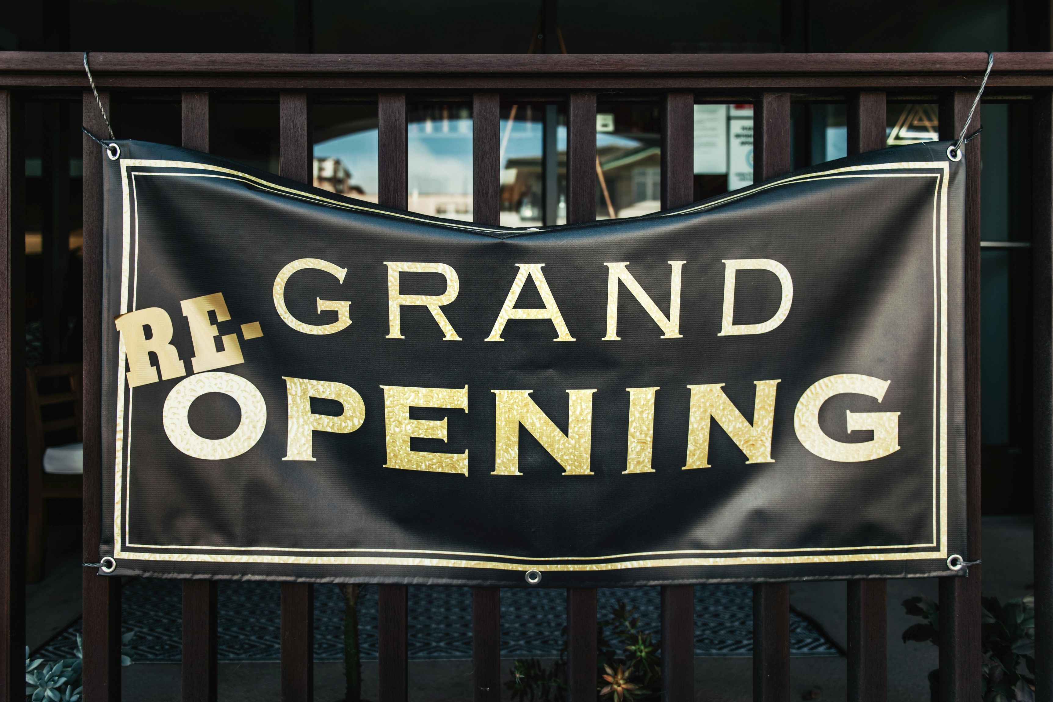 Black and gold outdoor banner announcing a re-opening